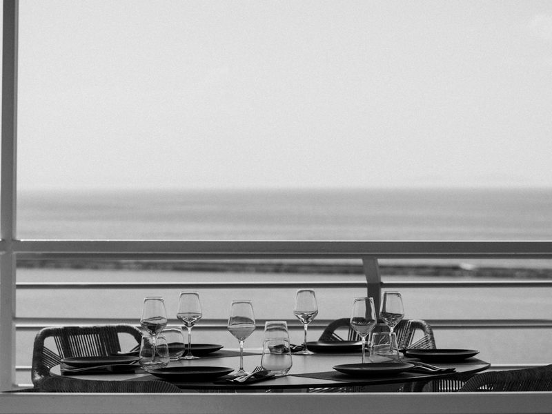 A table with glasses and plates on it by the water