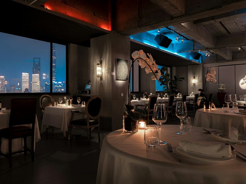 A dimly lit restaurant with a view of the city