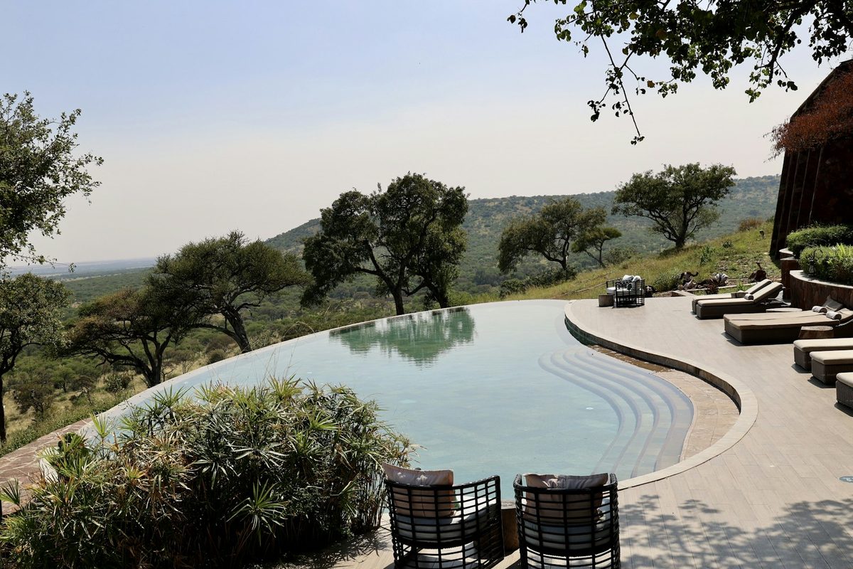 A pool with a patio and chairs