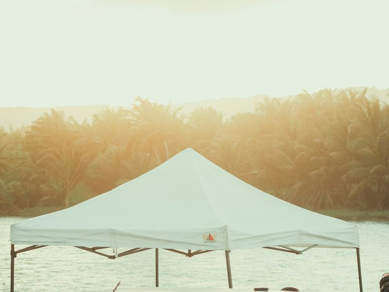 White canopy tent set up by the water at sunset