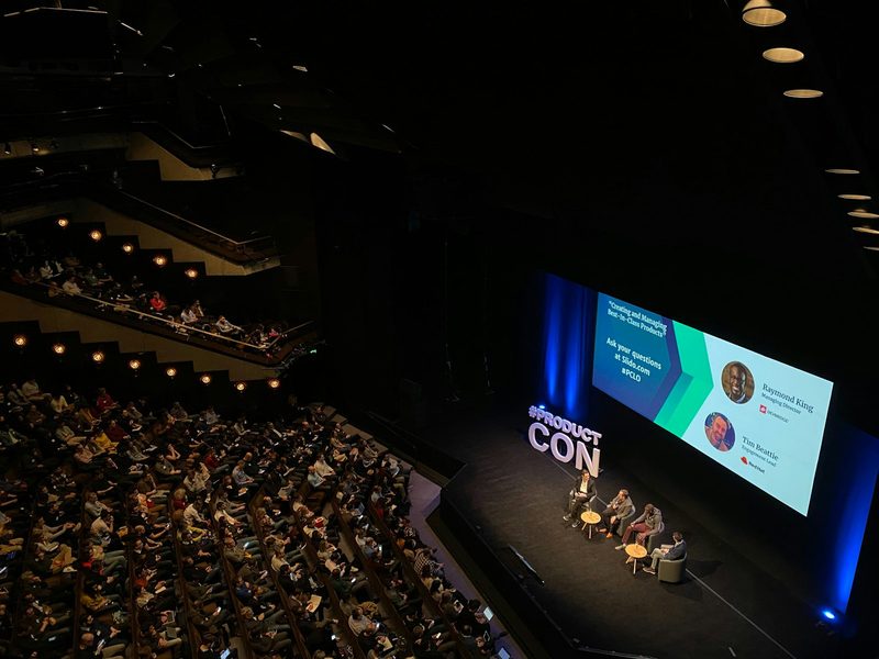 A panel discussion on a stage in a large auditorium with an audience (illustrative photo)