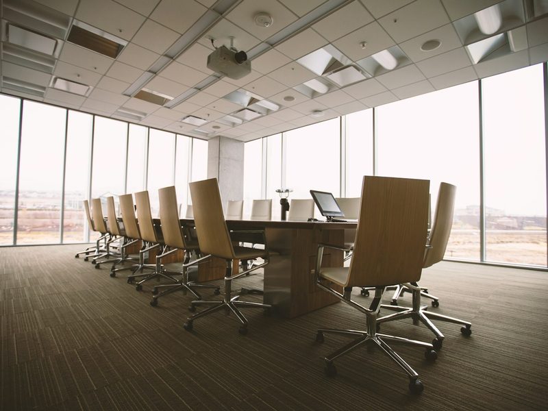 Oval brown wooden conference table and chairs inside conference room