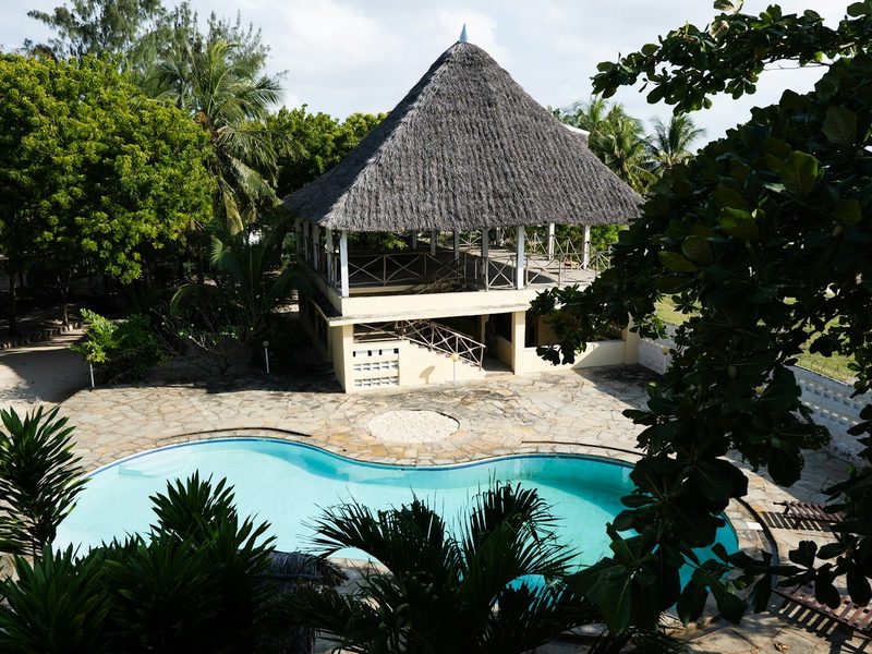 Thatched roof pavilion overlooks a tropical resort swimming pool