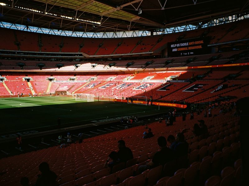 Empty soccer stadium with red seats and green field (illustrative photo)