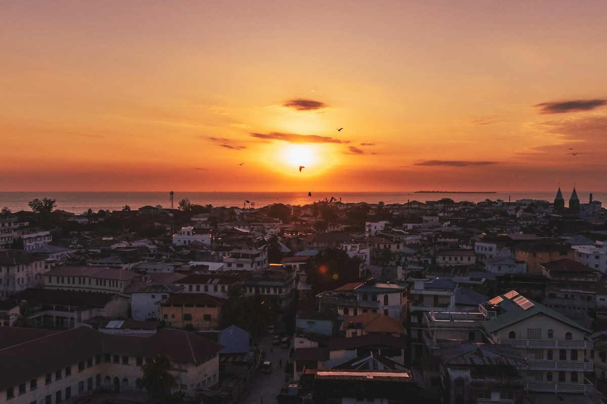 The sun is setting over a city by the ocean