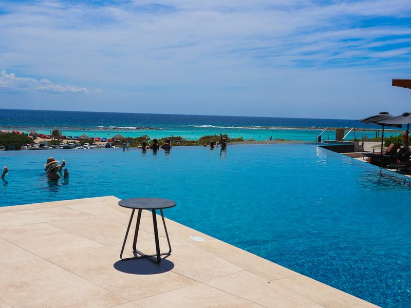 Infinity pool overlooking a turquoise ocean with people swimming