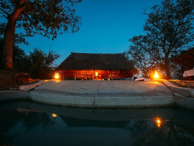Illuminated safari lodge with a pool at dusk