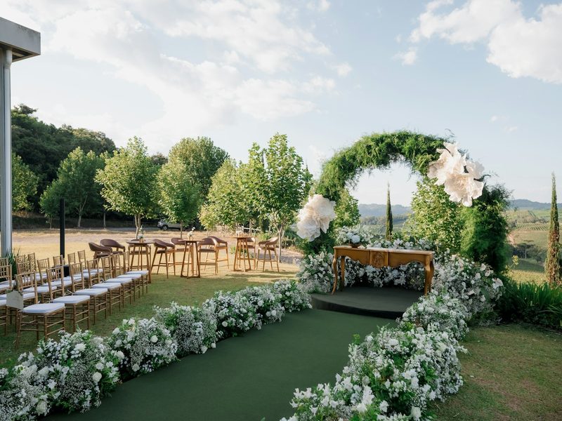 Outdoor wedding ceremony setup with floral arch and green arch
