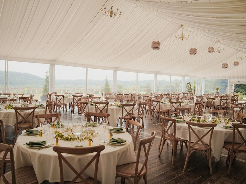 Elegant wedding reception tent with round tables and chairs