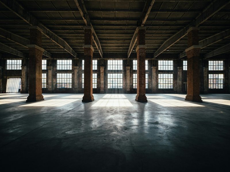Sunlight streaming into an empty industrial warehouse