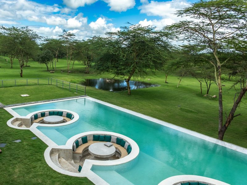 Modern swimming pool with unique seating areas in green landscape